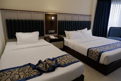 a hotel room with two beds and a chair at D'more Kuakata Hotel & Resort in Kuākāta
