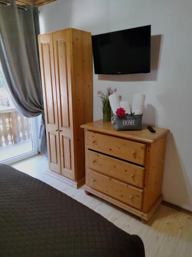 a bedroom with a dresser with a tv on a wall at Dor de Munte Transfăgarasan in Cîrţişoara