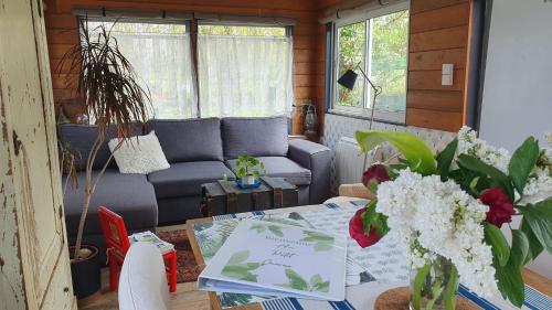 ein Wohnzimmer mit einem Sofa und einem Tisch mit Blumen in der Unterkunft Le Petit Cavron in Cavron-Saint-Martin