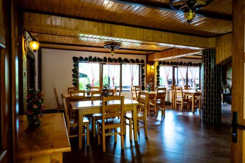 a restaurant with wooden tables and chairs and windows at Pensiunea Namaesti - Inchiriere integrala in Nămăeşti