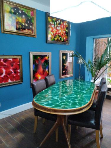 une salle à manger avec une table en verre et quelques peintures dans l'établissement Nuovo appartamento in borgo medievale, à Grosseto