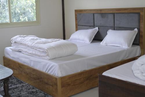 2 Betten mit weißer Bettwäsche und Kissen im Schlafzimmer in der Unterkunft Trishul Residency in Phata