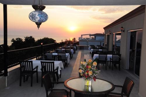 uma fila de mesas e cadeiras numa varanda com o pôr-do-sol em Beachway Hotel Side em Side