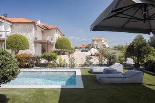 een achtertuin met een zwembad en een parasol bij Tyros Boutique Houses Villas in Tiros