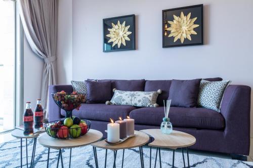 a living room with a purple couch and two tables with candles at Isrentals Haneviim - ApartHotel In City Center in Jerusalem