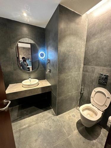 a bathroom with a toilet and a sink and a mirror at The Urban Suites in Ghaziabad