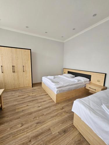 two beds in a white room with wooden floors at Shahumyan 98 Guest house in Gyumri