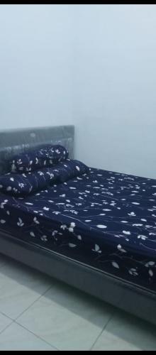 a bed with a blue comforter with flowers on it at Homestay selvi in Tlekung