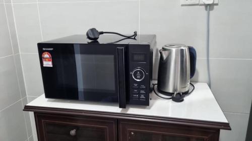 a microwave sitting on top of a counter with a silver appliance at Noble Vivacity Jazz 2 Cozy Homestay in Kuching