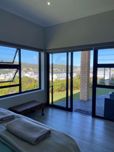 1 dormitorio con 1 cama y grandes ventanas de cristal en River Daze, en Stilbaai