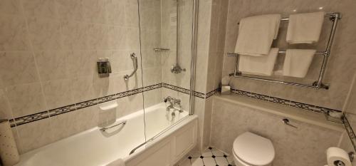 a bathroom with a tub and a toilet and a shower at Macdonald Lochanhully Resort in Carrbridge