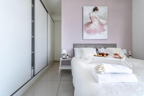 a white bedroom with a bed with a tray of food on it at Isrentals Haneviim - ApartHotel In City Center in Jerusalem