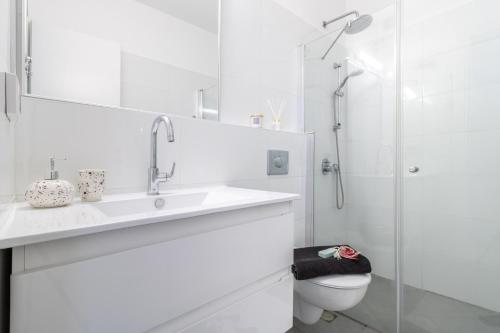 a white bathroom with a sink and a shower at Isrentals Haneviim - ApartHotel In City Center in Jerusalem