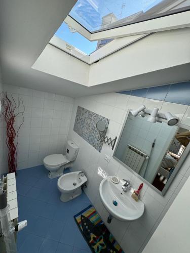 a bathroom with a sink and a toilet and a skylight at Le Tre Capanne in Marina di Carrara