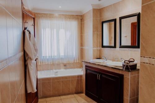 een badkamer met een bad, een wastafel en een bad tubermottermott bij Inkungu Lodge in Champagne Valley
