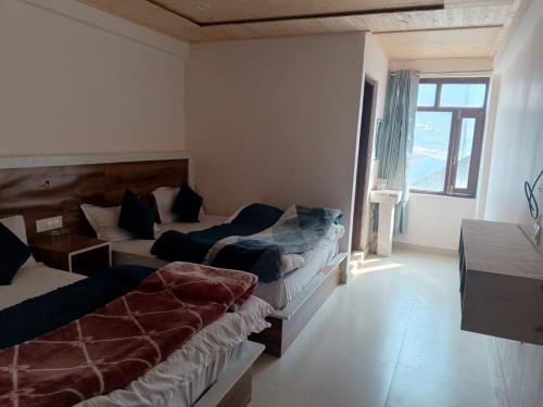 Habitación de hotel con 2 camas y ventana en Hotel Geeta Inn, en Badrīnāth