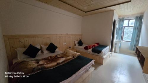 a bedroom with two beds and a window at Hotel Geeta Inn in Badrīnāth