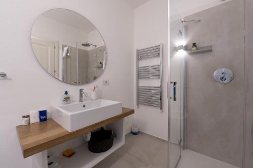 a white bathroom with a sink and a mirror at Sardinia Gold Luxury Apartment in Palau