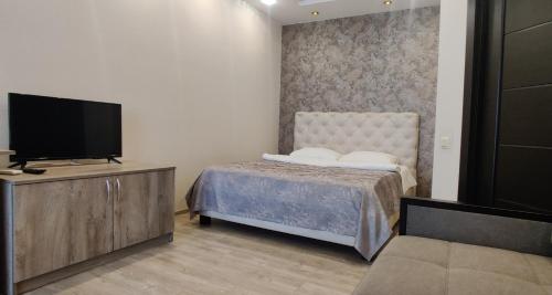 Schlafzimmer mit einem Bett und einem Flachbild-TV in der Unterkunft Сучасні апартаменти in Luzk
