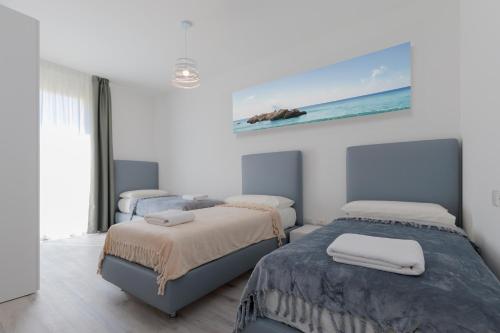 a bedroom with two beds and a painting on the wall at Wave Island! Luxury resort a Jesolo - Piscina e Park free! in Lido di Jesolo