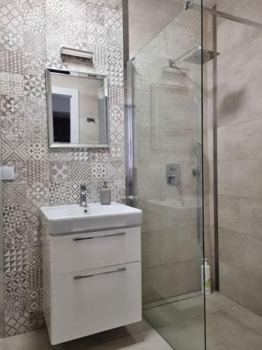 a bathroom with a sink and a shower with a mirror at Apartament Rejtana in Leszno