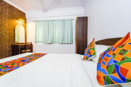 a bedroom with a bed with white sheets and colorful pillows at FabHotel Springs in Sangolda