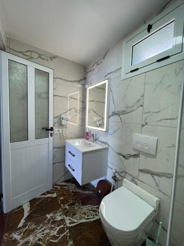a bathroom with a white toilet and a sink at Panorama Sea View Apartments in Vlorë
