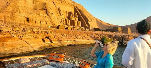 a woman taking a picture of a boat in the water at Sama Stars Hotel in Abu Simbel