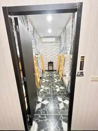 a hallway with a black and white tile floor at Economy Class Hostel in Dayuan