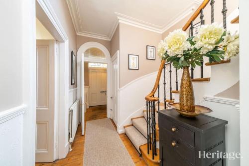 a hallway with a staircase with a vase of flowers at Fountainhall Luxury Townhouse, Aberdeen City Centre in Aberdeen