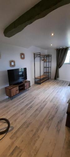 a living room with a flat screen tv and a wooden floor at demeure de charme in Mazères