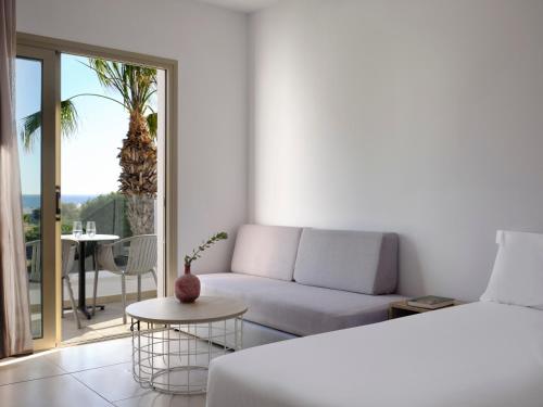 a white room with a bed and a couch and a table at Atlantica Panthea Resort in Ayia Napa