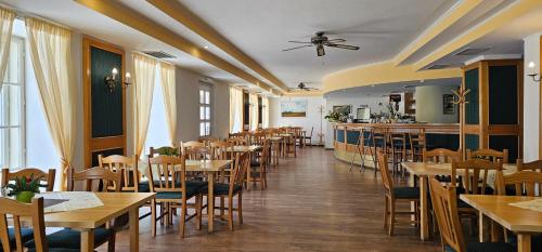 a restaurant with wooden tables and chairs and a bar at Zamecky Hotel Lednice in Lednice
