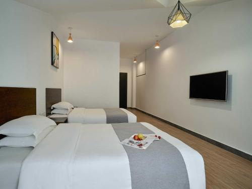 a hotel room with two beds and a flat screen tv at Zhangjiajie Yeah Hostel in Zhangjiajie