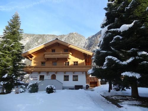 a house in the snow with trees and mountains at Ferienwohnungen Tiroler Haus in Mayrhofen