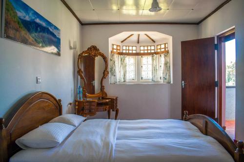 a bedroom with a bed and a mirror and a window at Mount Mary Inn in Nuwara Eliya
