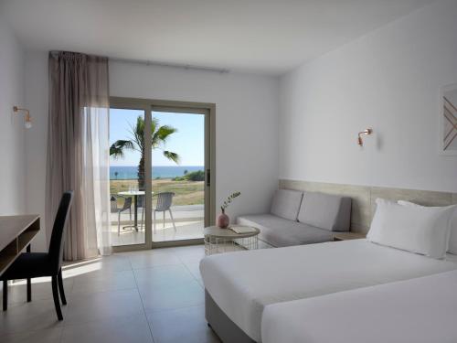 ein Schlafzimmer mit einem Bett, einem Sofa und einem Tisch in der Unterkunft Atlantica Panthea Resort in Ayia Napa