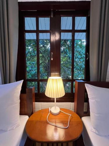 a lamp on a table in a room with two beds at Naisang Hostel in Chumphon