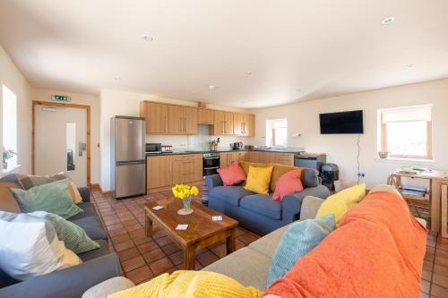 a living room with two couches and a kitchen at Spacious 6 bedroom property on a working fruit farm in Tore