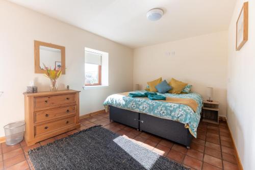 a bedroom with a bed and a dresser and a mirror at Spacious 6 bedroom property on a working fruit farm in Tore