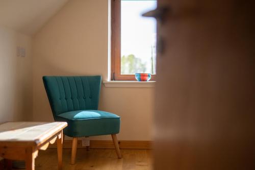 a green chair sitting in a room with a window at Spacious 6 bedroom property on a working fruit farm in Tore