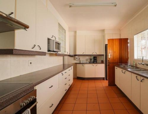 a kitchen with white cabinets and a orange tile floor at Lovely Holiday in Kempton Park