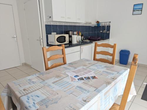 une cuisine avec une table et des chaises et un micro-ondes dans l'établissement Appart' avec grande terrasse vue mer -50m plage et du sentier de randonnée, à Planguenoual