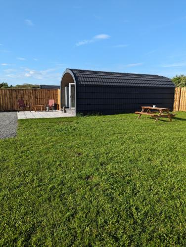 a backyard with a black building and a picnic table at My Happy Hounds Glamping in Northallerton