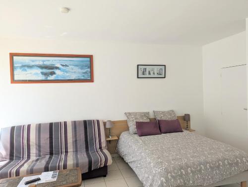 une chambre avec un lit et un canapé dans l'établissement Appart' avec grande terrasse vue mer -50m plage et du sentier de randonnée, à Planguenoual