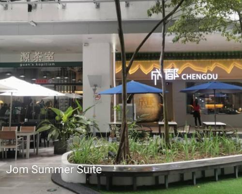 a restaurant with tables and umbrellas in front of a building at Jom Summer Suite - Sutera Avenue in Kota Kinabalu