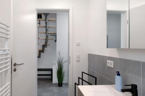 La salle de bains est pourvue de murs blancs, d'un lavabo et d'un escalier. dans l'établissement Müritzblick, à Vipperow