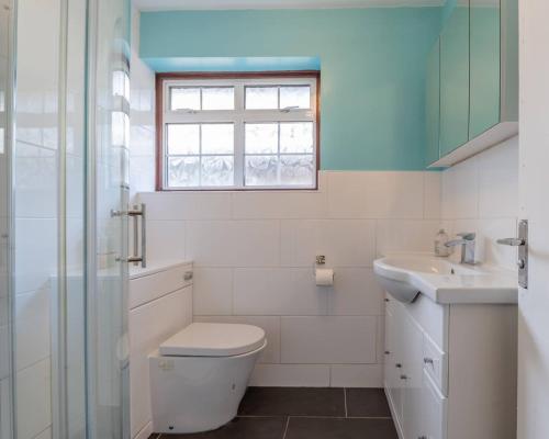 a bathroom with a toilet and a sink and a window at Pass the Keys Large house in Benfleet in South Benfleet