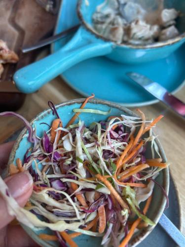 a person holding a blue bowl of coleslaw at Уютный номер с видом на горы in Makhinjauri