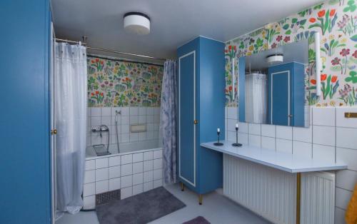 uma casa de banho com armários azuis, um lavatório e um chuveiro em Mysigt HÄRBRE STUGA med utsikt över Siljan em Rättvik